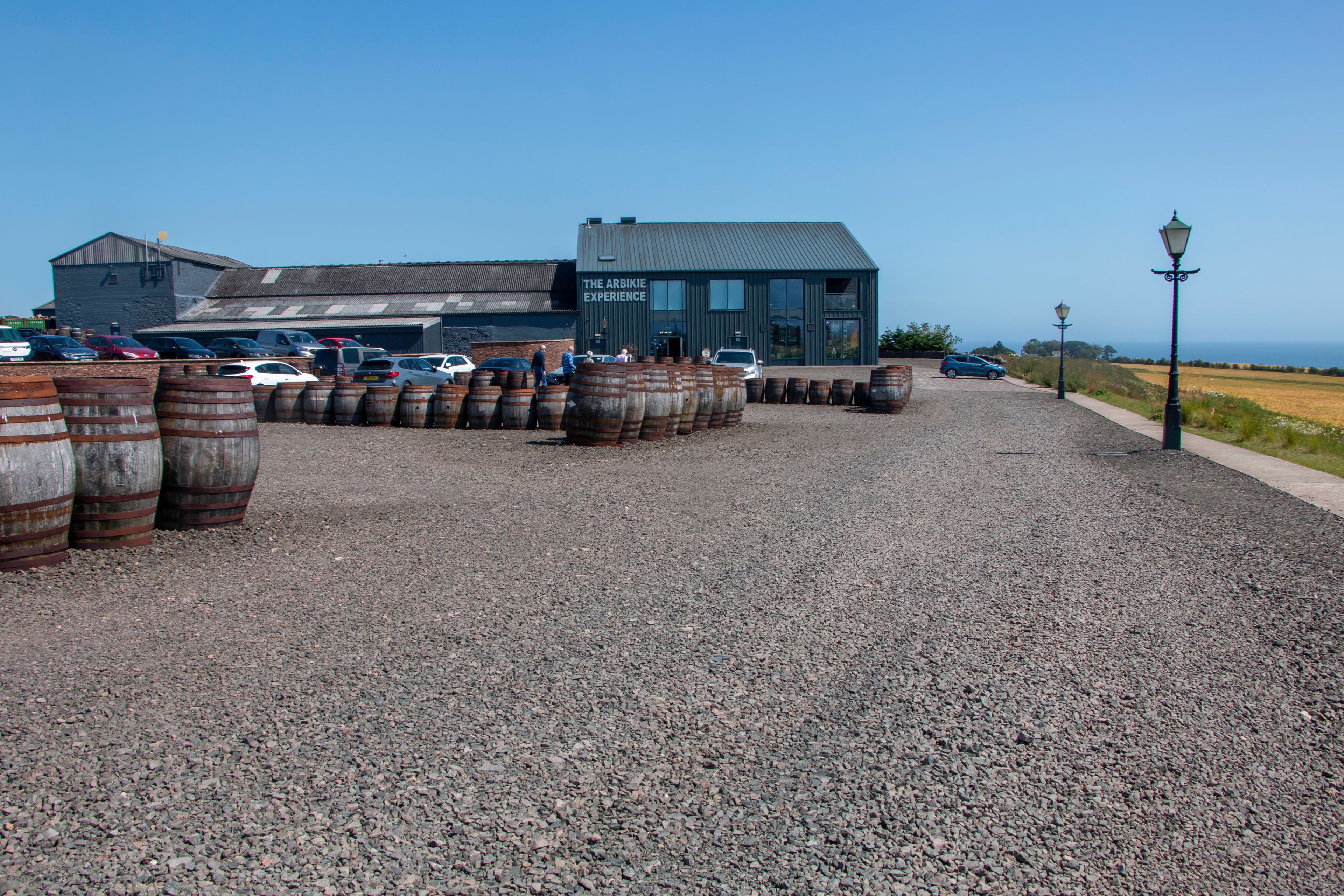 Casks in the yard at Arbikie Distillery, Angus, with the sea beyond the fields