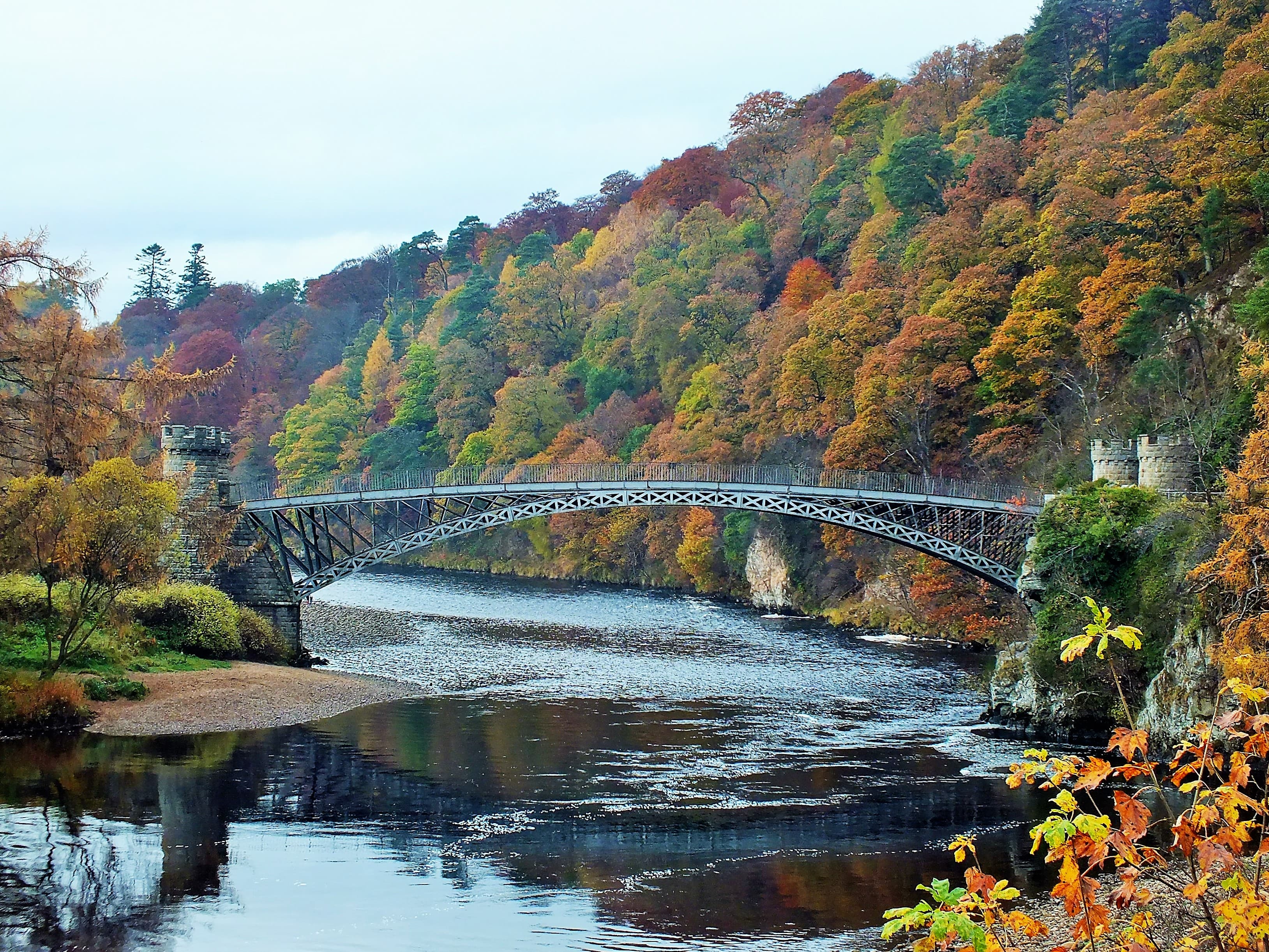 The Telford bridge over the River Spey at Craigellachie, autumn colour on the wooded banks