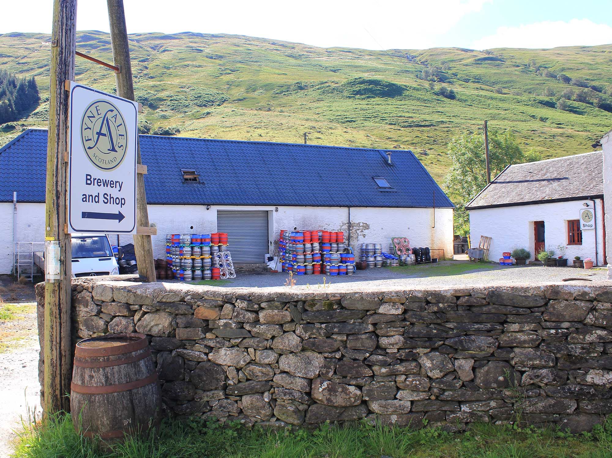 Fyne Ales brewery and shop, white farm buildings with stacked casks below the hills of Glen Fyne
