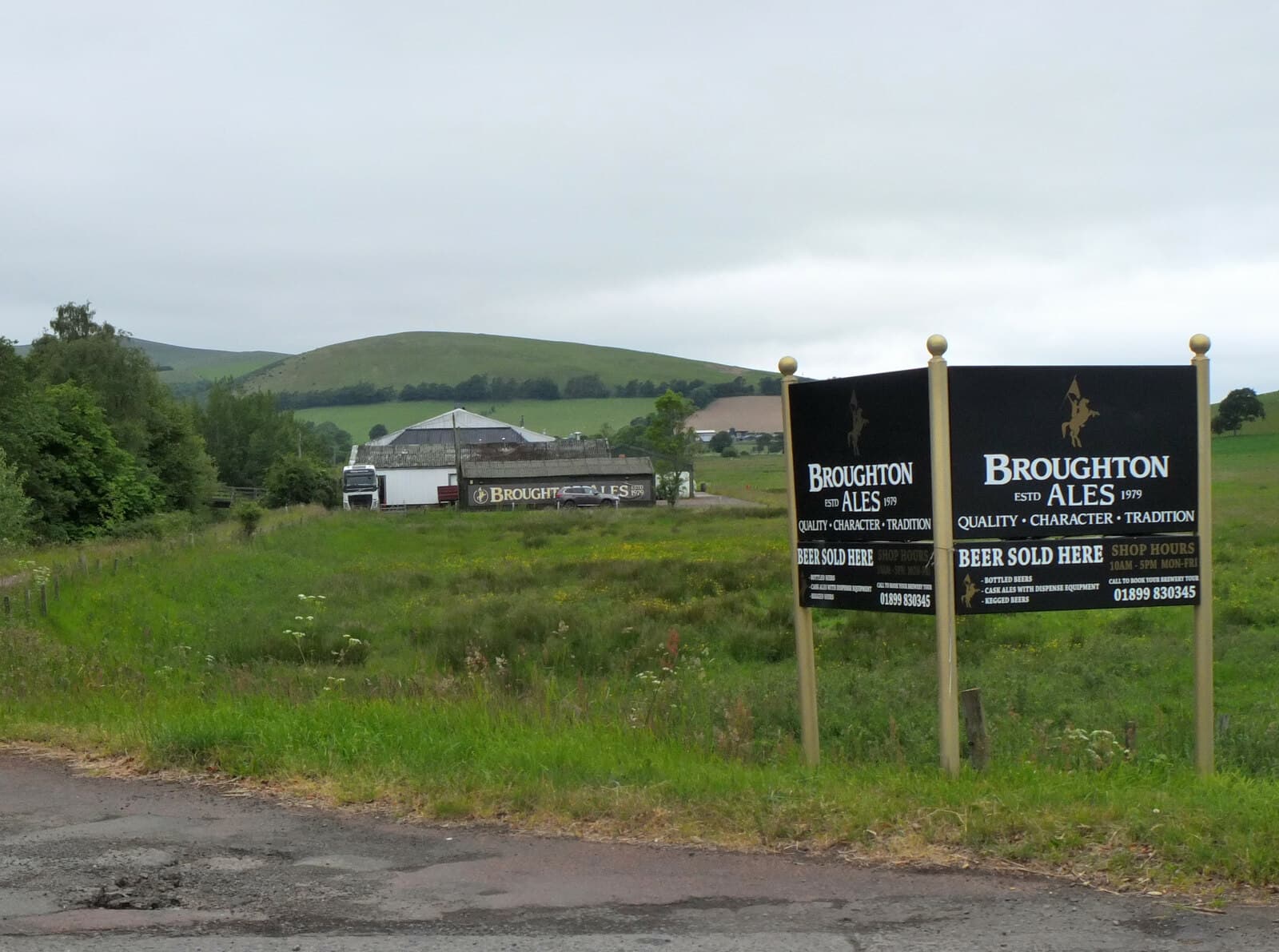 Broughton Ales signs at the roadside, the brewery and the Broughton Heights behind