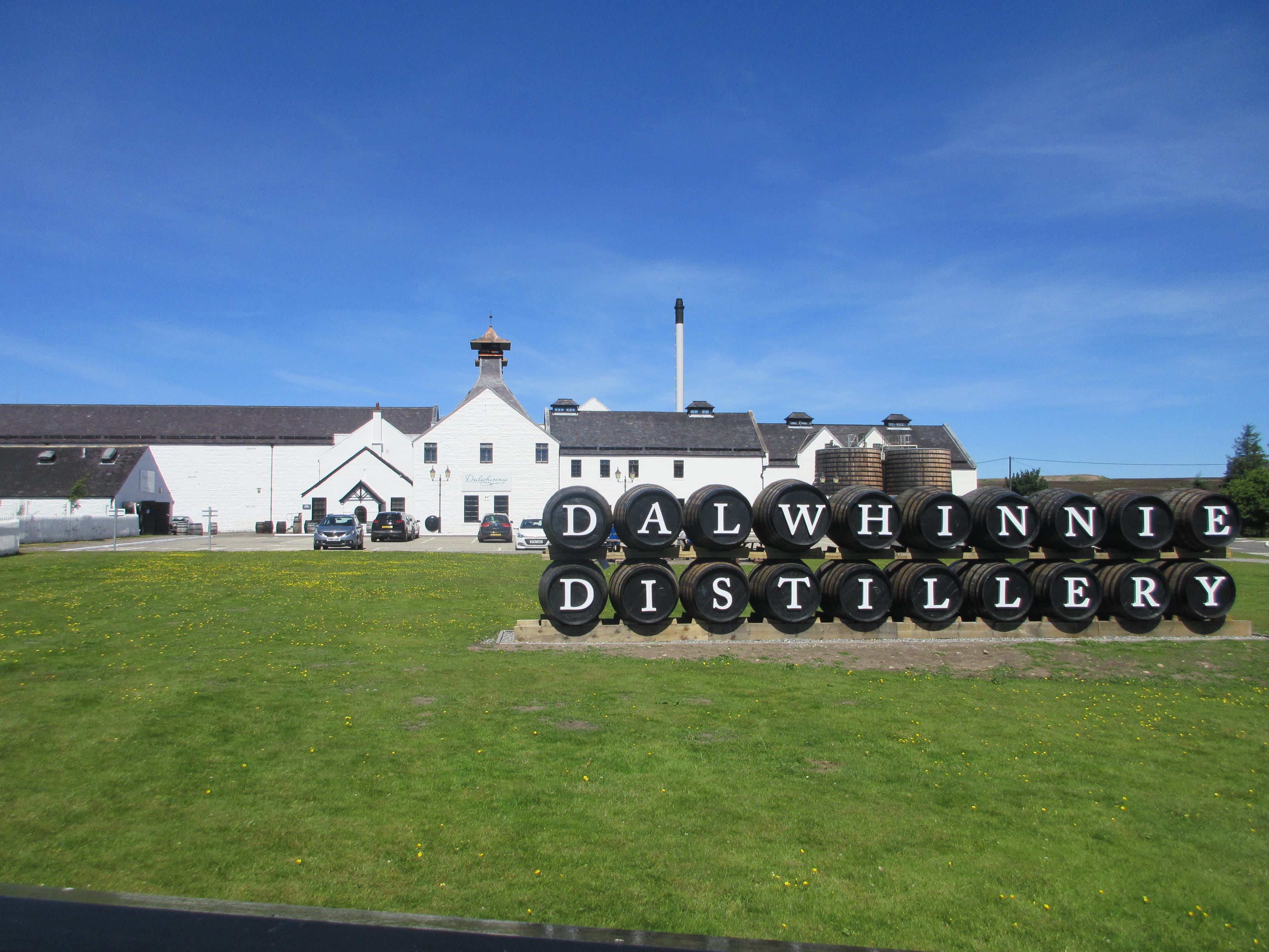 Dalwhinnie distillery's white buildings and twin pagodas behind the entrance sign