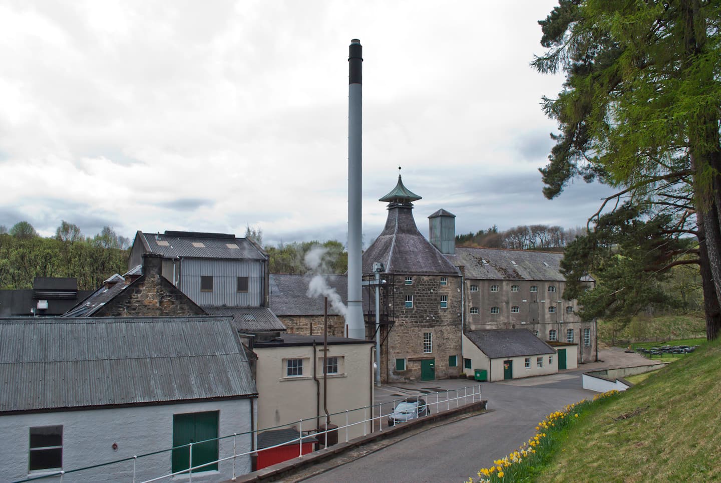 Speyburn distillery's chimney and pagoda roof in its wooded glen near Rothes