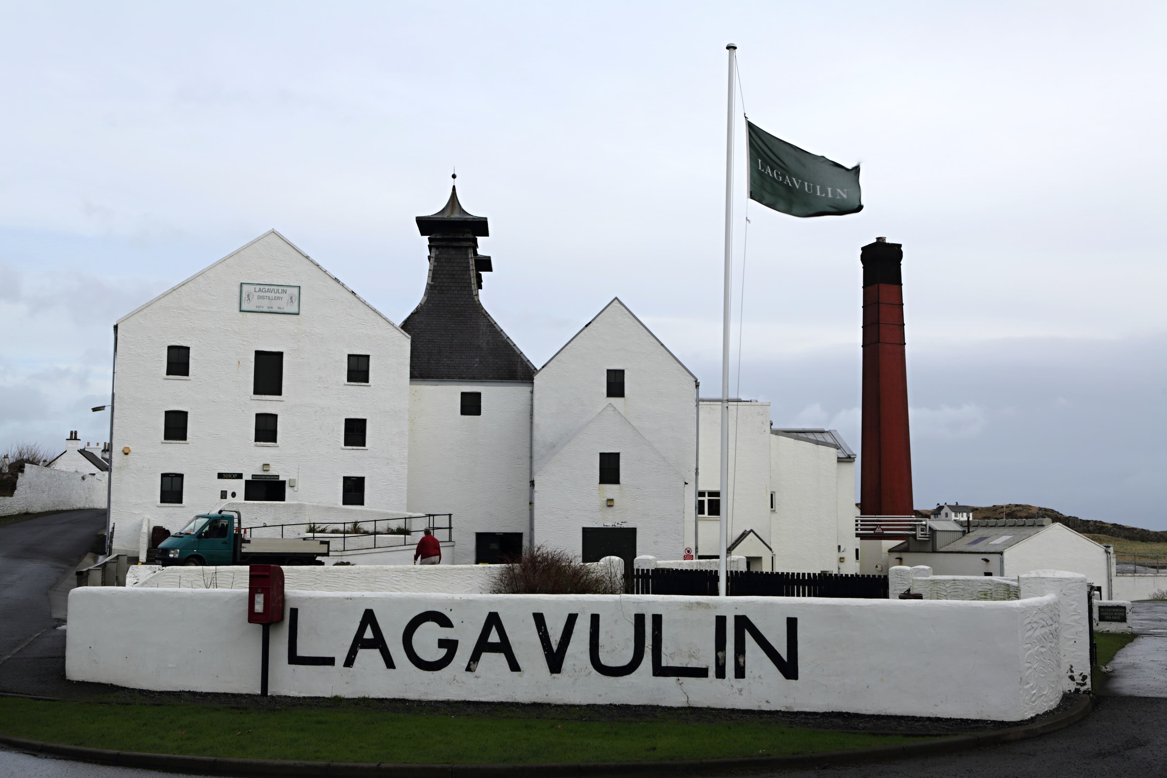 Lagavulin distillery's white shore-side buildings with the name painted on the sea wall
